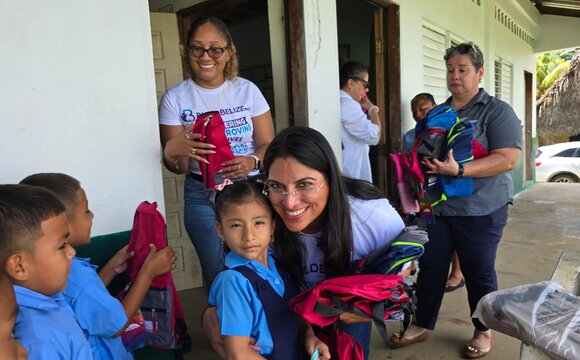A Build Belize volunteer handing new backpacks to primary school pupils
