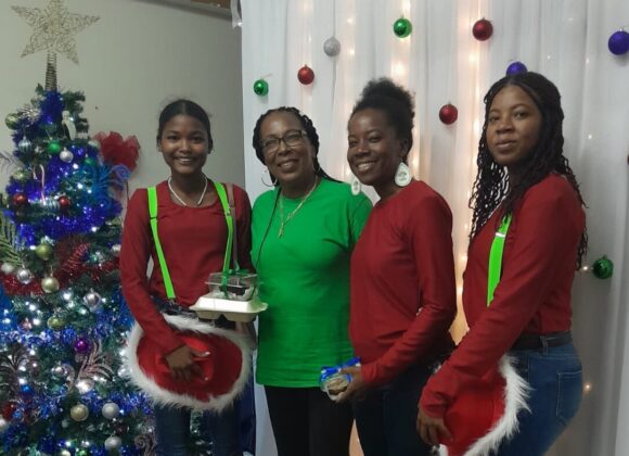 Guests gathered beside a Christmas tree at a Build Belize holiday party