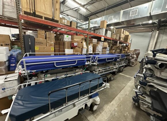 Donated hospital beds and medical equipment staged in a warehouse
